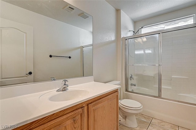 full bathroom featuring visible vents, toilet, combined bath / shower with glass door, a textured ceiling, and vanity