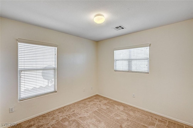 spare room featuring baseboards, visible vents, and light colored carpet