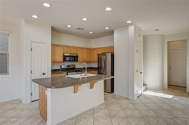 kitchen featuring a breakfast bar area, recessed lighting, appliances with stainless steel finishes, a sink, and an island with sink