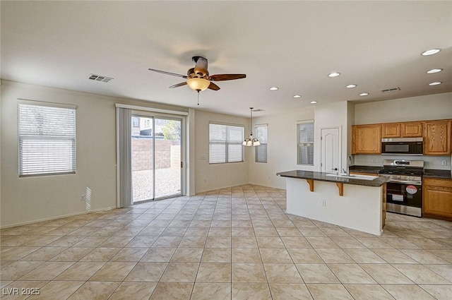 kitchen with appliances with stainless steel finishes, dark countertops, a breakfast bar, and visible vents