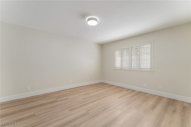 empty room featuring baseboards and light wood-style floors