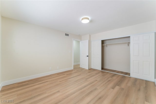 unfurnished bedroom featuring a closet, visible vents, light wood-style flooring, and baseboards