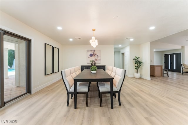 dining area with light wood-type flooring, visible vents, and baseboards