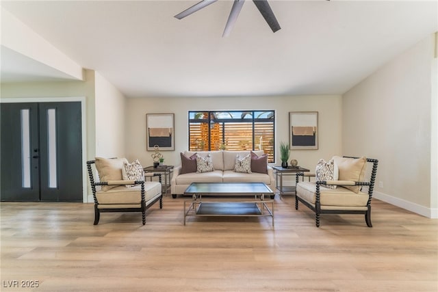 living area with light wood-style floors, ceiling fan, baseboards, and french doors