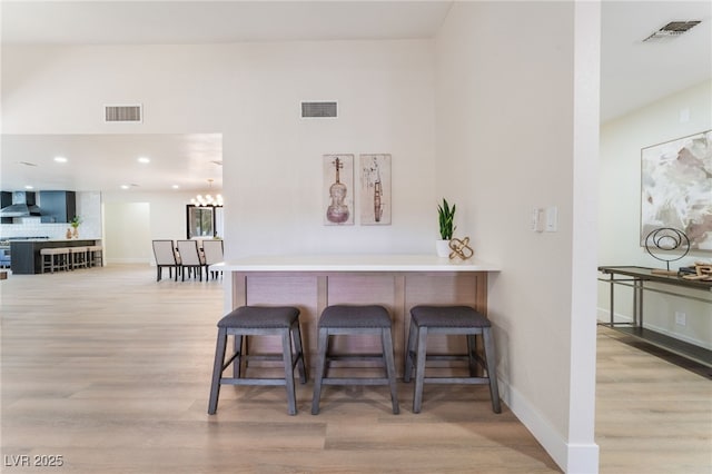 interior space with wall chimney range hood, light wood-style flooring, and visible vents