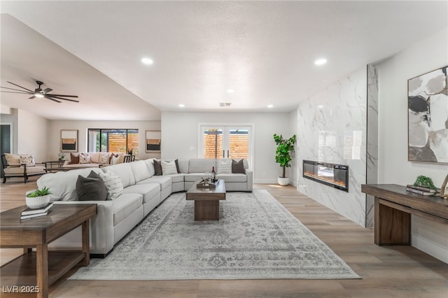 living area with visible vents, ceiling fan, wood finished floors, a fireplace, and recessed lighting