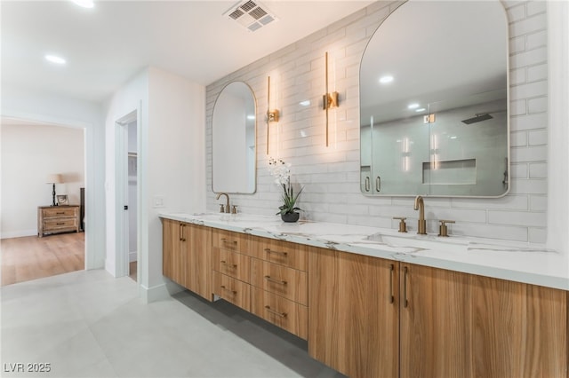 bathroom featuring double vanity, backsplash, a sink, and visible vents