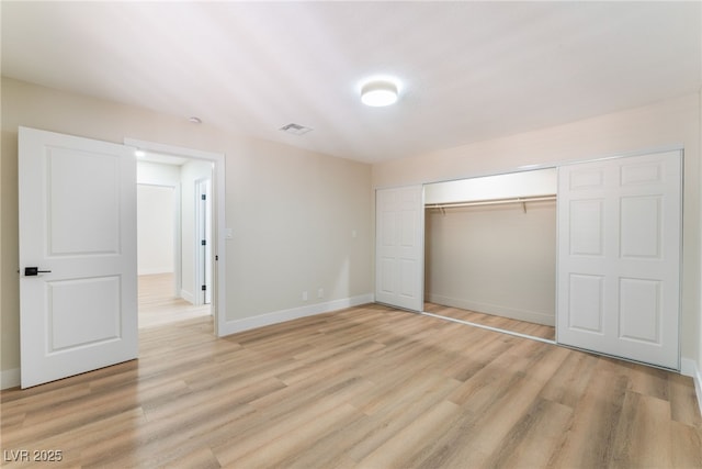 unfurnished bedroom with light wood-style flooring, visible vents, baseboards, and a closet