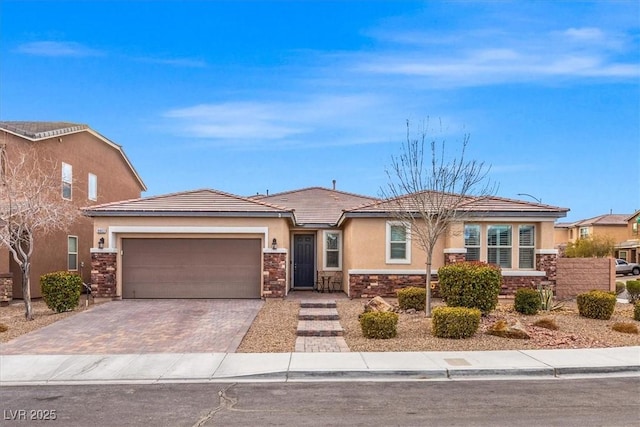 view of front of property featuring decorative driveway, stone siding, a garage, and stucco siding