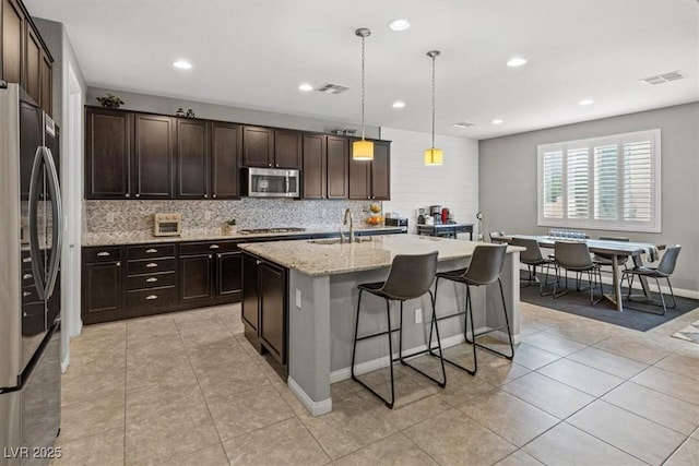 kitchen featuring light tile patterned floors, tasteful backsplash, visible vents, appliances with stainless steel finishes, and a sink