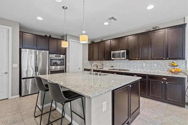 kitchen with stainless steel appliances, a sink, visible vents, dark brown cabinets, and decorative backsplash