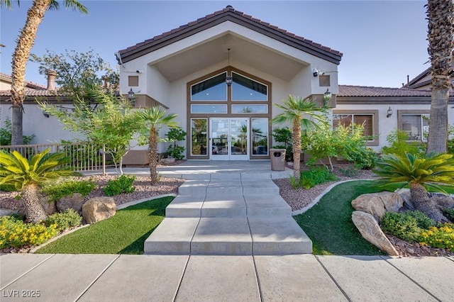 entrance to property with french doors, a tiled roof, and stucco siding