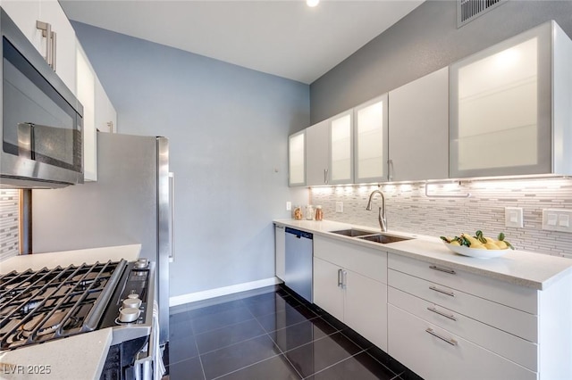 kitchen featuring tasteful backsplash, appliances with stainless steel finishes, light countertops, white cabinetry, and a sink