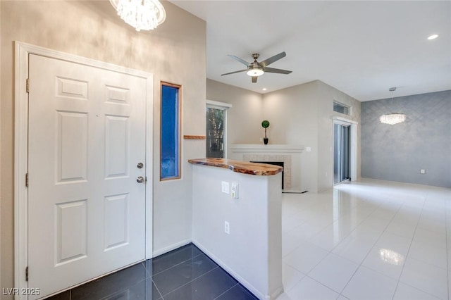 foyer entrance featuring visible vents, dark tile patterned flooring, ceiling fan with notable chandelier, a fireplace, and recessed lighting