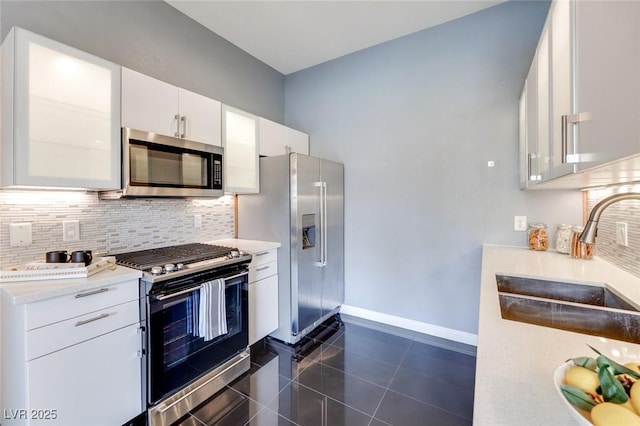 kitchen featuring white cabinets, appliances with stainless steel finishes, a sink, light countertops, and backsplash