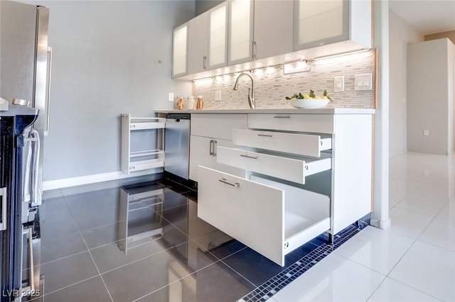 kitchen with tasteful backsplash, white cabinets, light countertops, and dark tile patterned floors