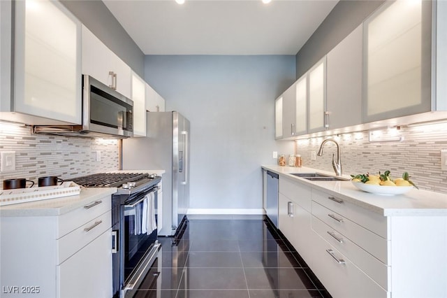 kitchen featuring light countertops, appliances with stainless steel finishes, white cabinets, a sink, and dark tile patterned floors