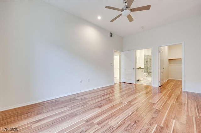 unfurnished bedroom featuring a closet, light wood-type flooring, a walk in closet, and baseboards