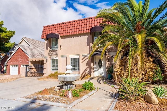 mediterranean / spanish home featuring a tile roof, stucco siding, concrete driveway, a gate, and a garage