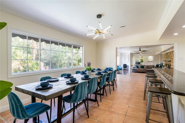 dining area featuring light tile patterned floors, ceiling fan with notable chandelier, visible vents, baseboards, and ornamental molding