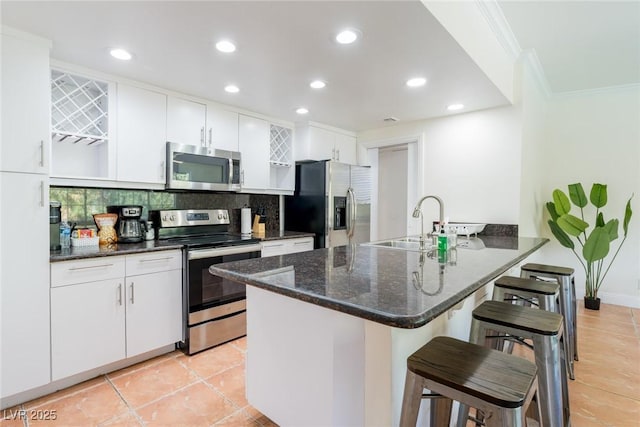 kitchen featuring stainless steel appliances, a breakfast bar, a peninsula, a sink, and backsplash