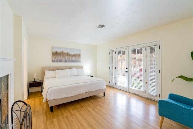 bedroom featuring a fireplace, visible vents, access to outside, french doors, and light wood-type flooring