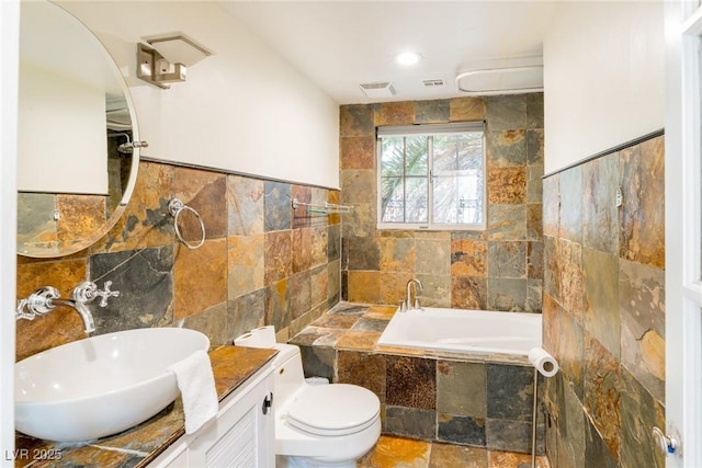 full bath featuring tile walls, visible vents, toilet, vanity, and a bath