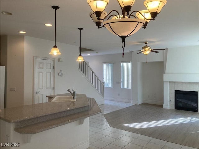 kitchen featuring open floor plan, light tile patterned floors, recessed lighting, a tile fireplace, and a sink