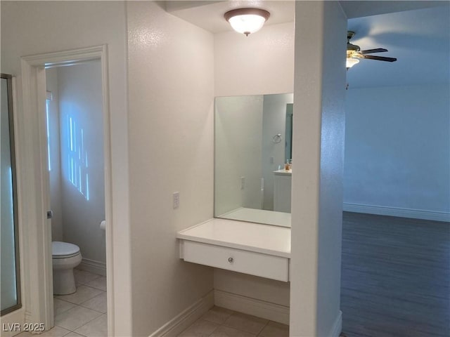 bathroom with baseboards, toilet, and tile patterned flooring