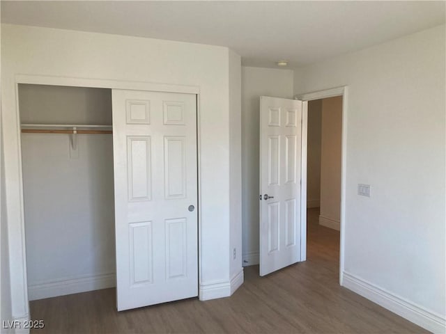 unfurnished bedroom with a closet, baseboards, and wood finished floors