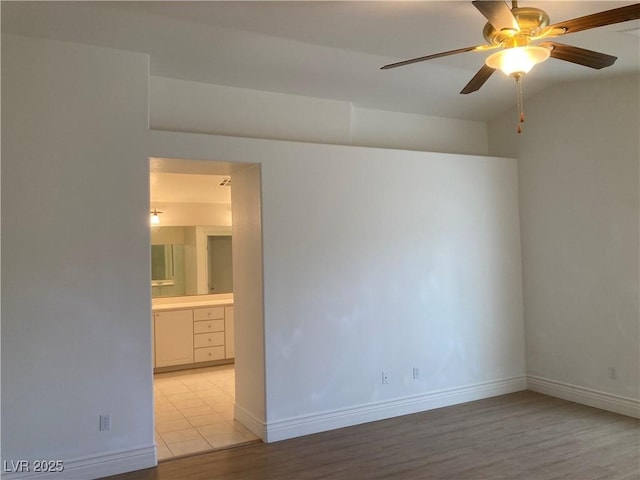 empty room featuring baseboards, light wood-type flooring, and ceiling fan