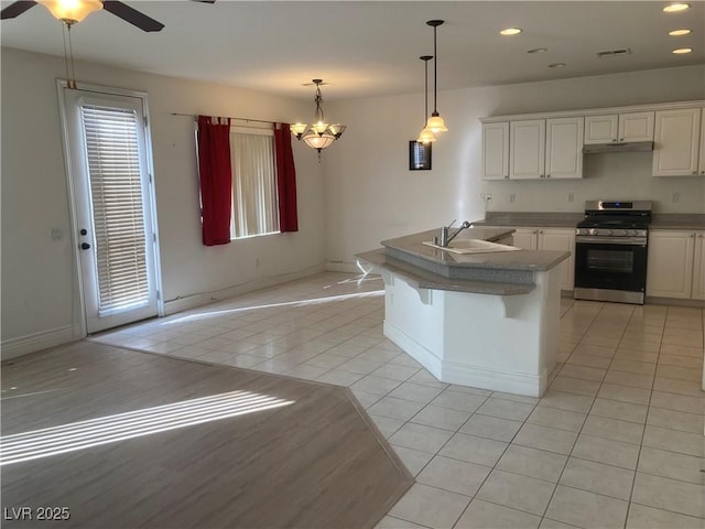 kitchen featuring stainless steel range with gas cooktop, under cabinet range hood, light tile patterned floors, recessed lighting, and a sink