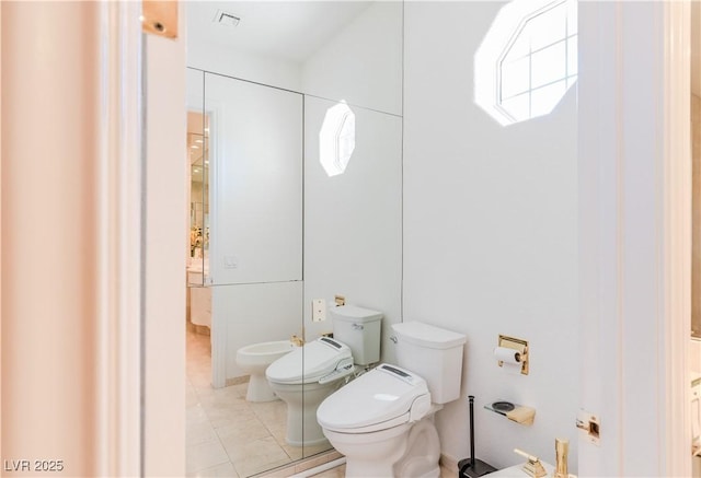 bathroom with a bidet, toilet, and tile patterned floors