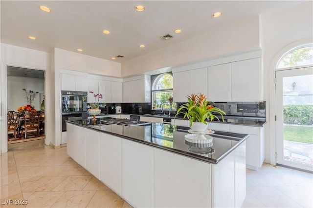 kitchen with tasteful backsplash, dark countertops, oven, and visible vents