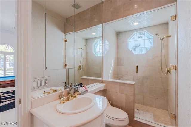 bathroom with toilet, a stall shower, vanity, and visible vents