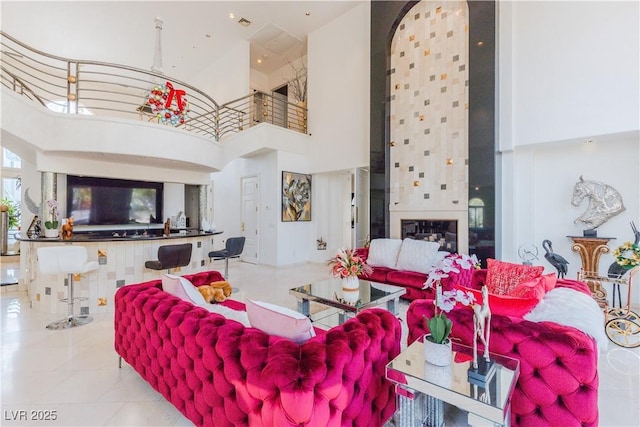 living area featuring a fireplace, tile patterned flooring, and a towering ceiling