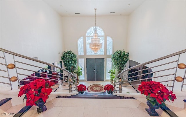 tiled entryway featuring a chandelier, stairway, and visible vents