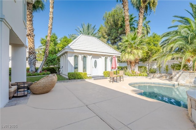 pool with a patio area, an outdoor structure, and fence