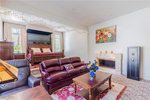 carpeted living area featuring baseboards and a high end fireplace