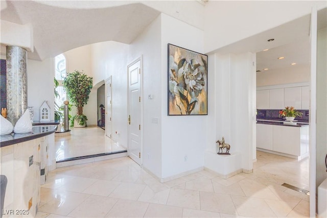 corridor featuring light tile patterned floors and baseboards