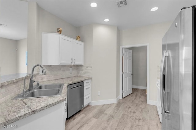 kitchen with visible vents, a sink, backsplash, light wood-style floors, and appliances with stainless steel finishes