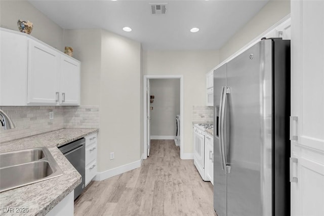 kitchen featuring visible vents, a sink, stainless steel appliances, light wood-style floors, and white cabinetry