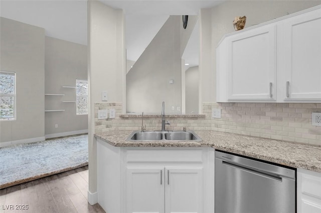 kitchen with a sink, white cabinets, stainless steel dishwasher, tasteful backsplash, and light wood-type flooring