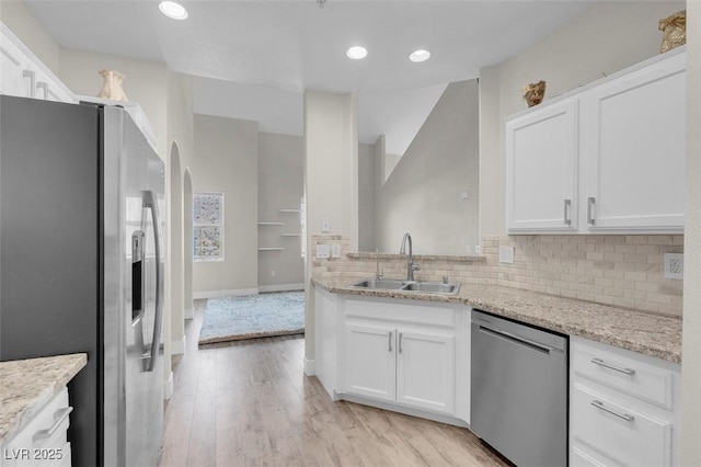 kitchen with decorative backsplash, white cabinets, stainless steel appliances, and a sink