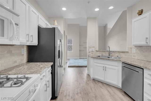 kitchen featuring a sink, white appliances, light wood-style flooring, and white cabinetry