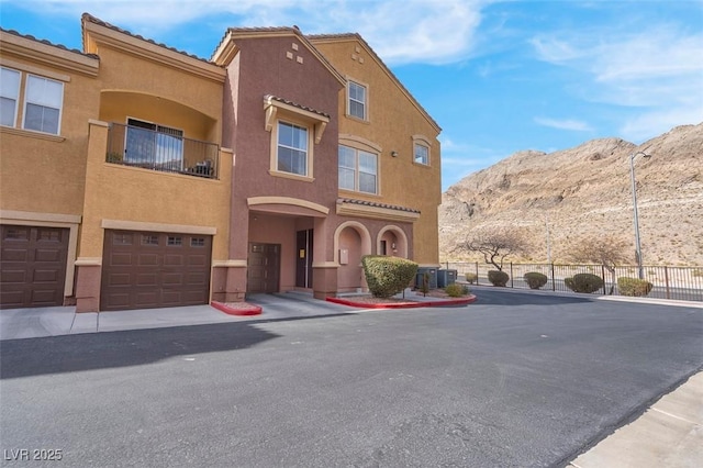 view of front of property with an attached garage, fence, stucco siding, cooling unit, and a mountain view