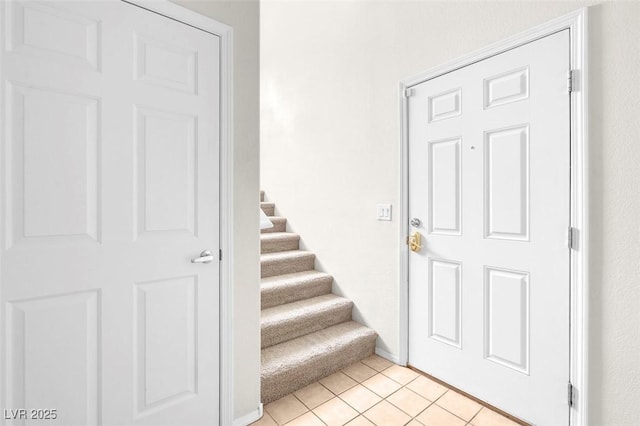 entryway with stairway, light tile patterned floors, and baseboards