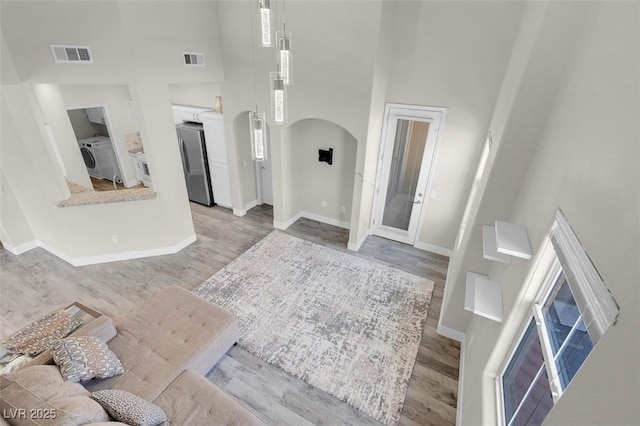 interior space with arched walkways, visible vents, washer / dryer, and a high ceiling