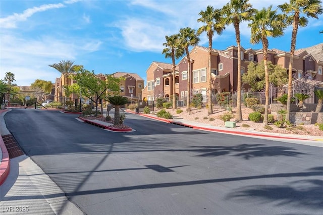 view of road featuring curbs, a gate, a gated entry, a residential view, and sidewalks