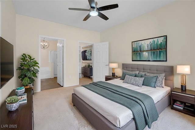 bedroom with a spacious closet, carpet flooring, ceiling fan with notable chandelier, and connected bathroom